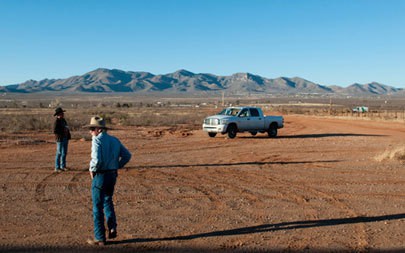 Rancher Dennis Moroney (right) and Alfredo Gonzalez at the southern border fence in Naco, Ariz. Gonzalez works with the USDA Jornada Experimental Range in Las Cruces N.M, and he delivers criollo bulls to Moroney's ranch just outside of Bisbee, Ariz. (Photo by Molly J. Smith)