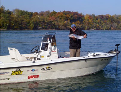 ldo Nava poses on his boat on the Niagara River, holding a steelhead trout he caught. Nava says the water in the river looks cleaner each year. Photo courtesy of Aldo Nava.