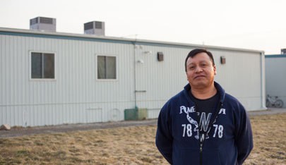 Eddie Lix, a guest worker from Guatemala stands in front of agricultural worker housing on a farm site in Ontario, Canada. Worker housing is a requirement under Canada's guest worker program. Photo by Perla Farias