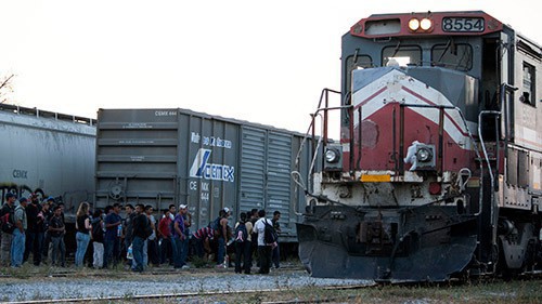 As the freight train, 'La Bestia' pulled into the 'station' in Arriaga, Chiapas Mexico, a large group of mainly young men gathered waiting for the conductors to finish connecting several cars before they climbed on top Friday March, 8, 2014. (Photo by Jessie Wardarski.)