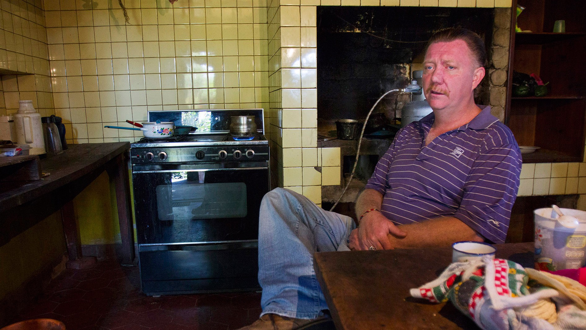 Virgil Edwards sits in the kitchen of a home that was half burned down by the invaders. (Photo by Connor Radnovich.)