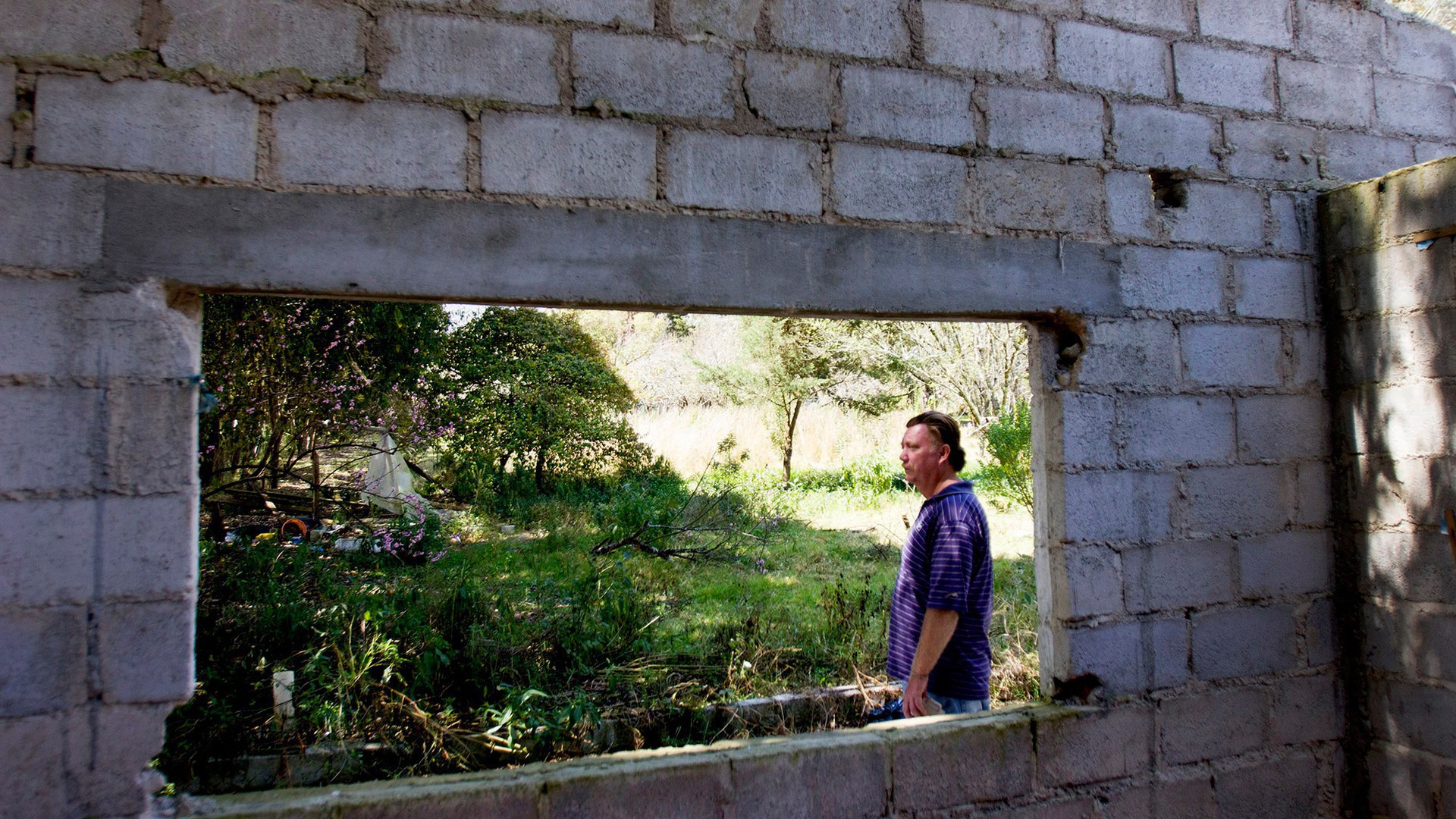 Virgil Edwards looks over an abandoned home on his land that was burned by the invaders. (Photo by Connor Radnovich.)