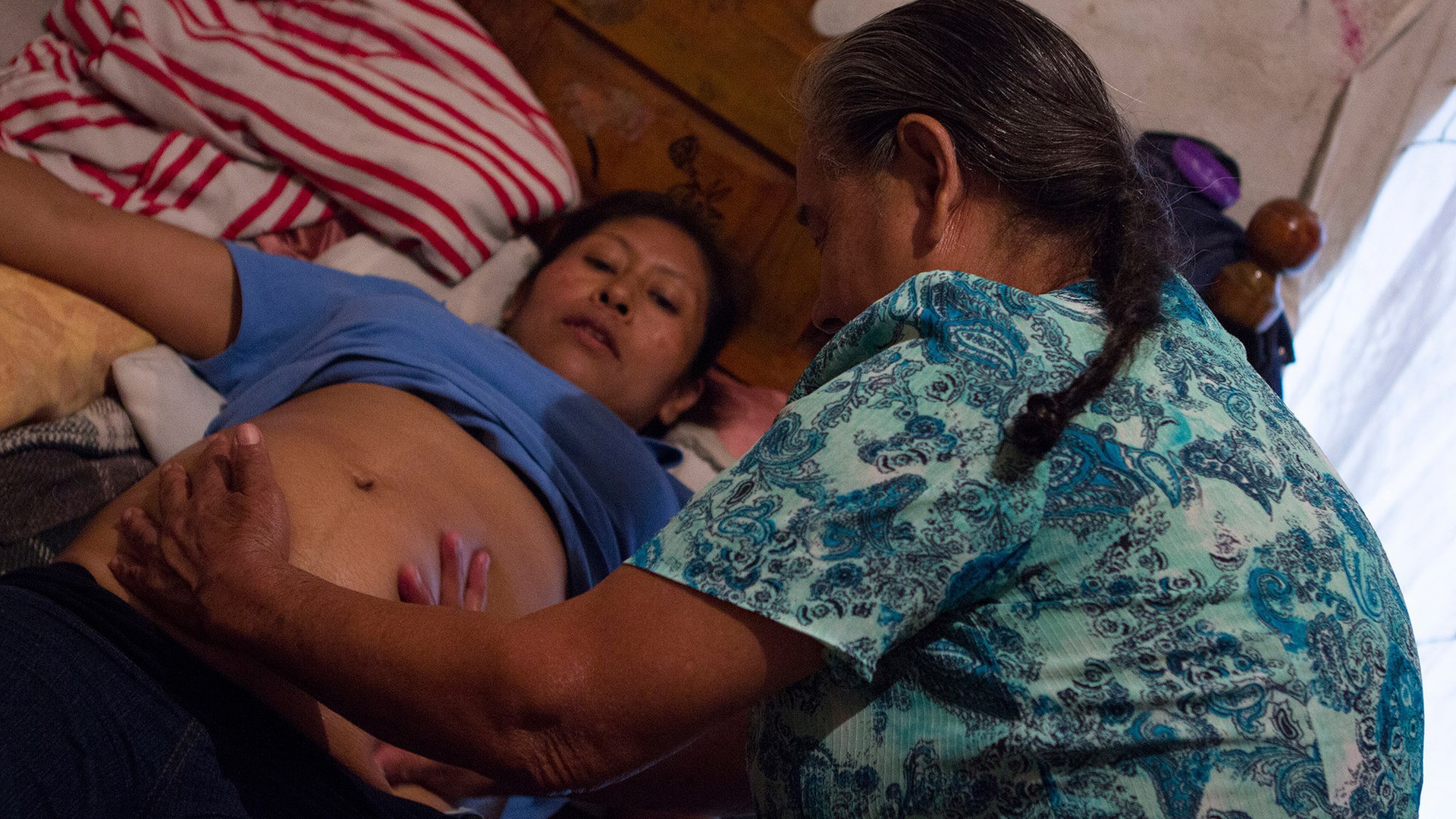 Doña Mercedes gives Maria Lopez Mendoza, then six months pregnant, a massage to check on her baby. (Photo by Alex Lancial.)
