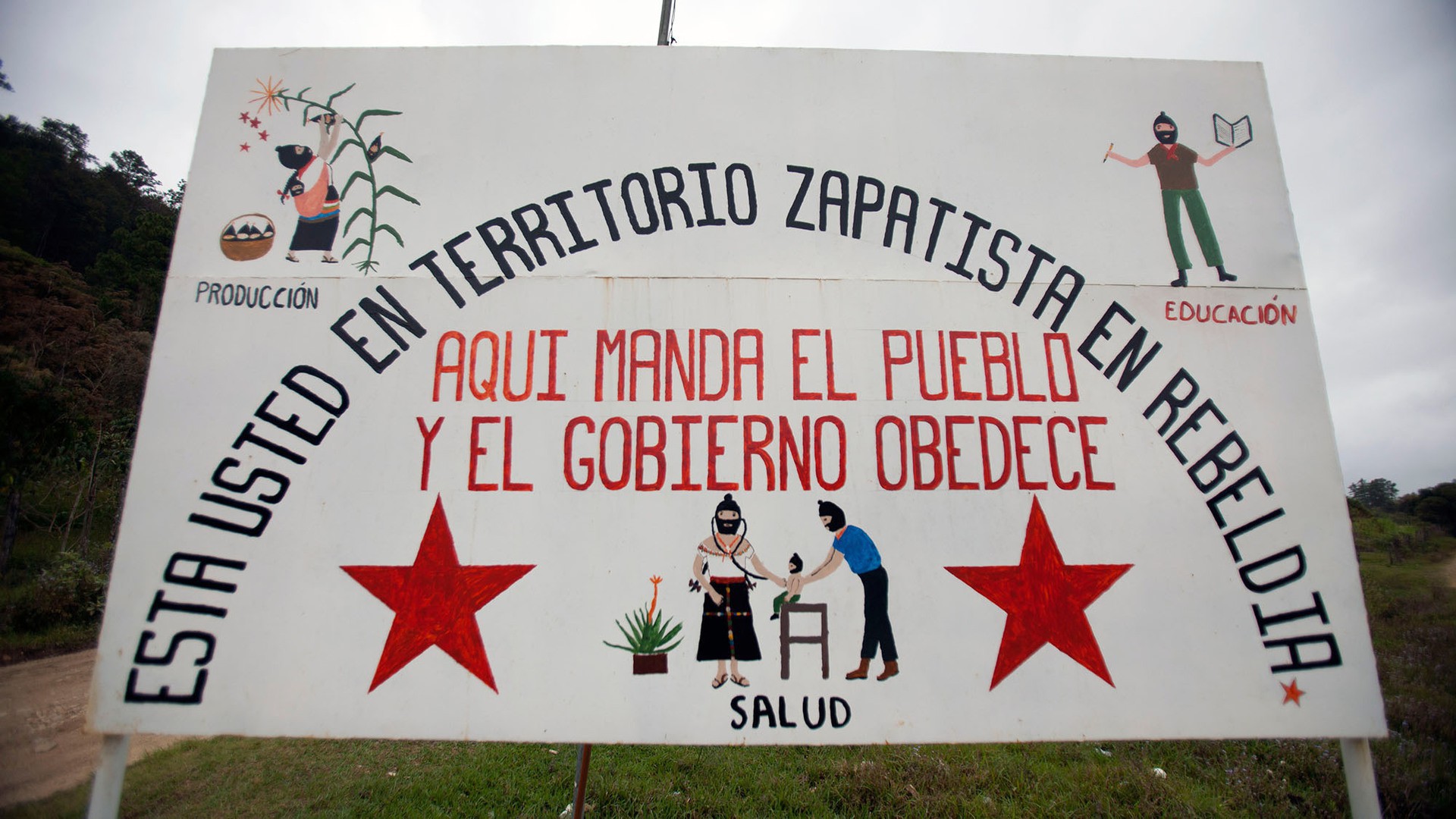 The sign at the gate to Caracol Morelia depicts the Zapatista lifestyle - production and agriculture, health and education. Visitors to the caracoles, the independent Zapatista communities, need to be approved by the Council of Good Governance before entry. (Photo by Connor Radnovich.)