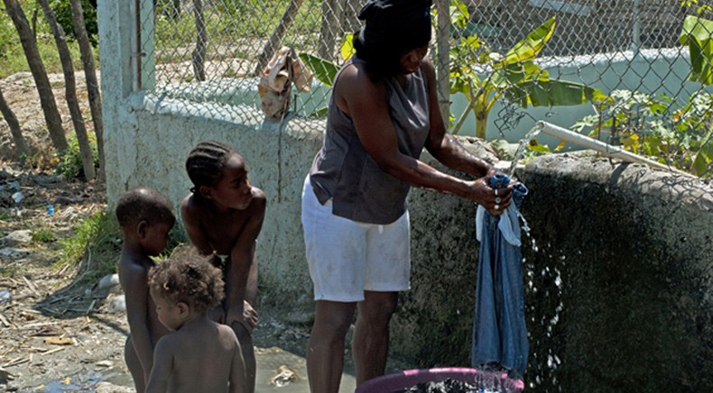 A family living in Batey 9 on the Dominican Republic’s border with Haiti washes clothes and bathes in the untreated but free water of the village’s communal cistern.