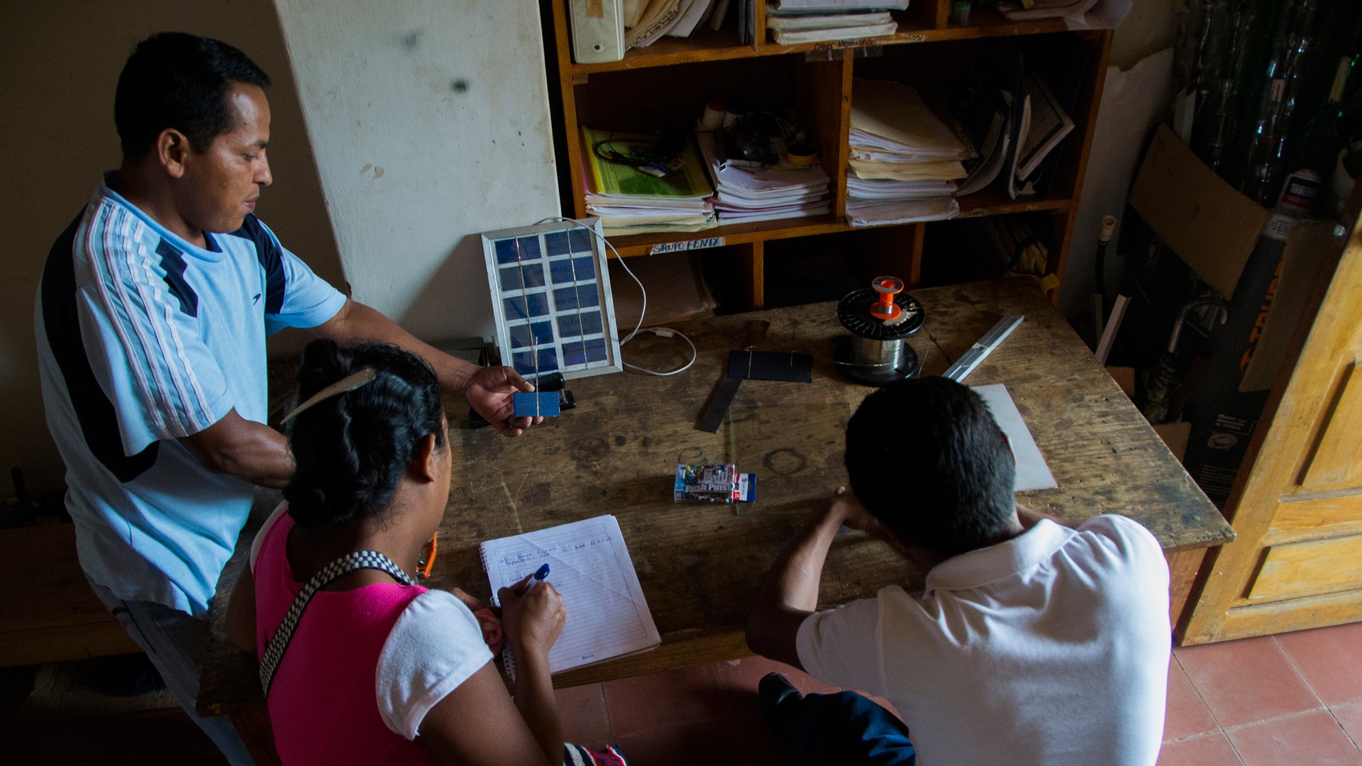 Jorge David López teaches two Grupo Fénix interns, Melvin Antonio Gonzalez and Erlinda deJesus Arroliga, how to build small solar panels for a group of students that will be visiting Sabana Grande, Nicaragua. Grupo Fénix trains international students and interns from the community to build and install solar panels on homes in the area that do not have electricity. (Photo by Danika Worthington)