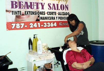 Rossy Santos, 38, takes care of a customer at her beauty salon “Kiarangely” located in Santurce. She came to Puerto Rico in a yola at the age of 31, leaving her then 12-year-old daughter, Melissa, behind. Photo by Khara Persad