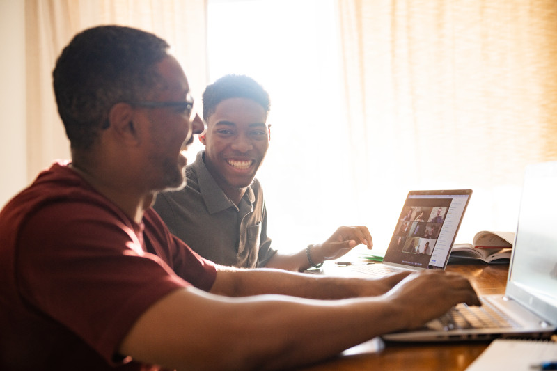 Two men talking while working on laptops.