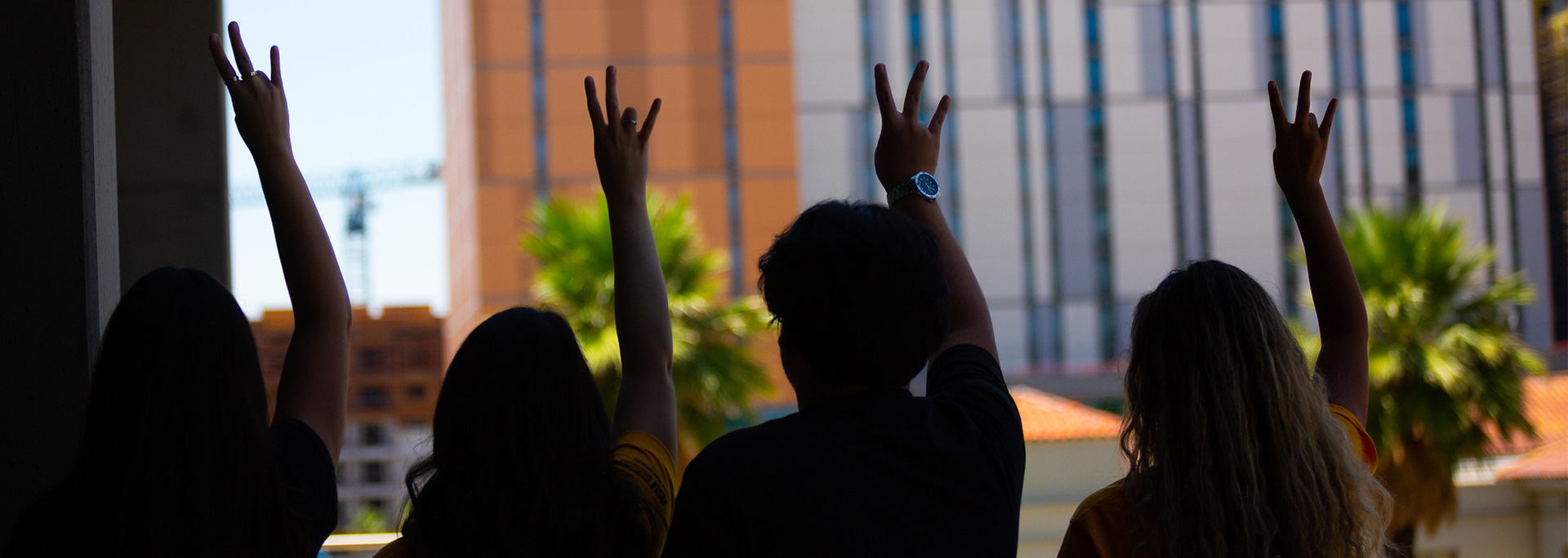 The silhouettes of four cronkite students holding up the ASU pitchfork.