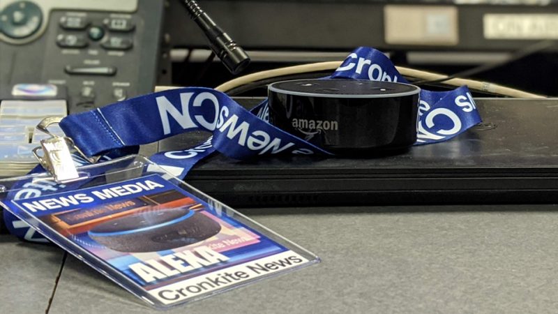 Amazon Echo Dot with a Cronkite News lanyard on a black laptop, next to a news media badge.