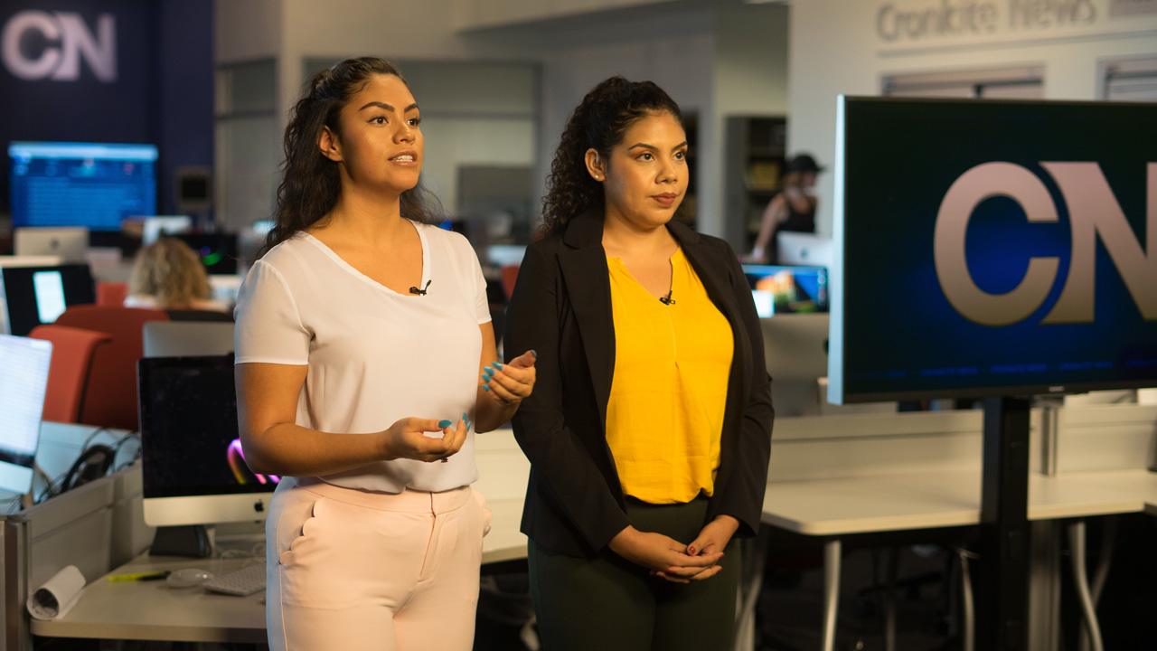 Two Cronkite Noticias reporters deliver the news on tv.
