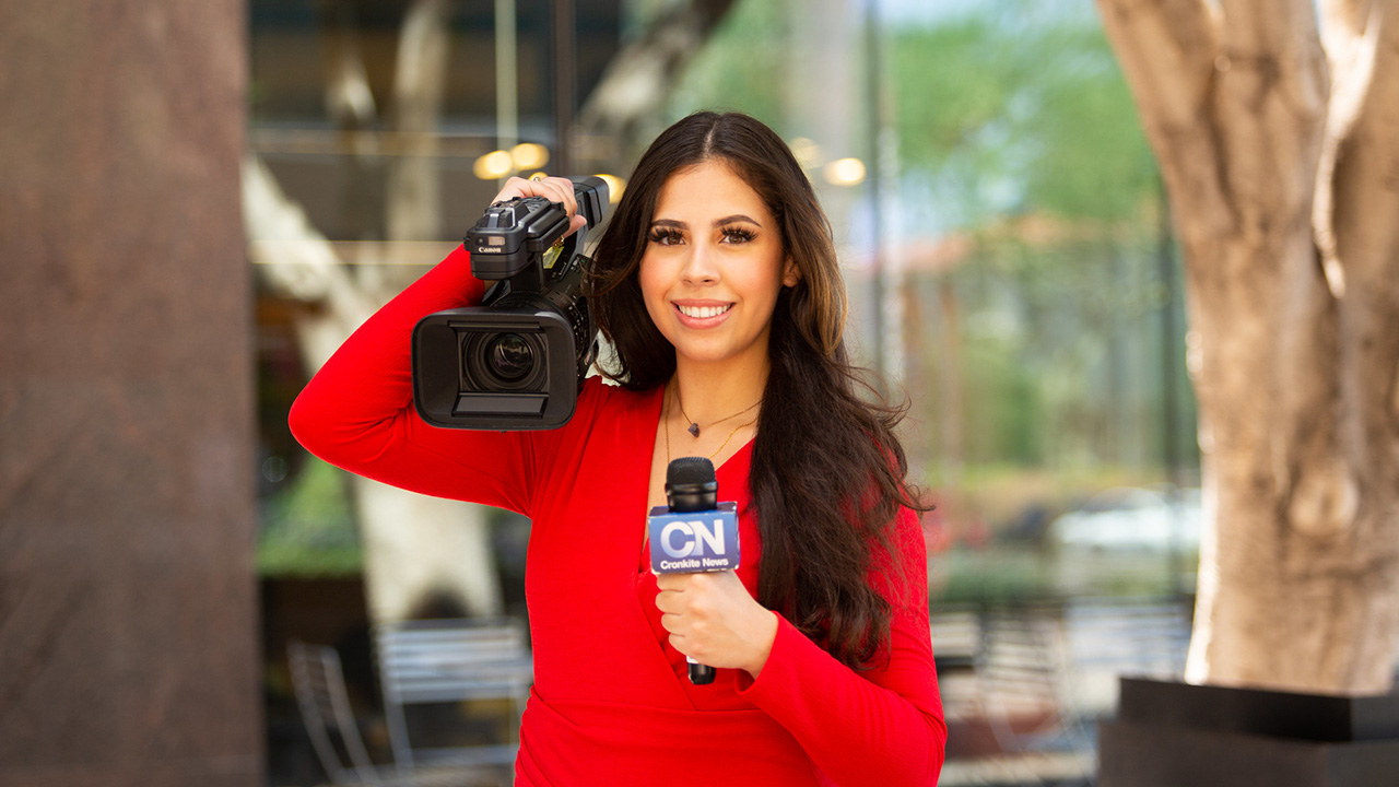 A Cronkite News reporter holds a camera and microphone.