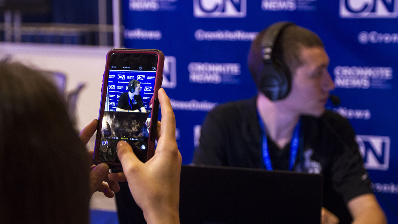 A student takes a photo of a reporter on a smart phone.