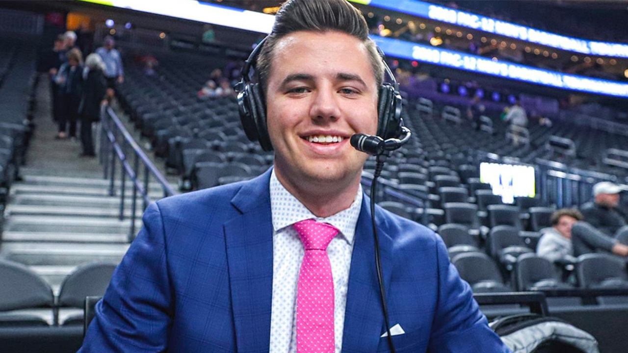 A student sits in the press box and wears a commentator headset at an NBA game.