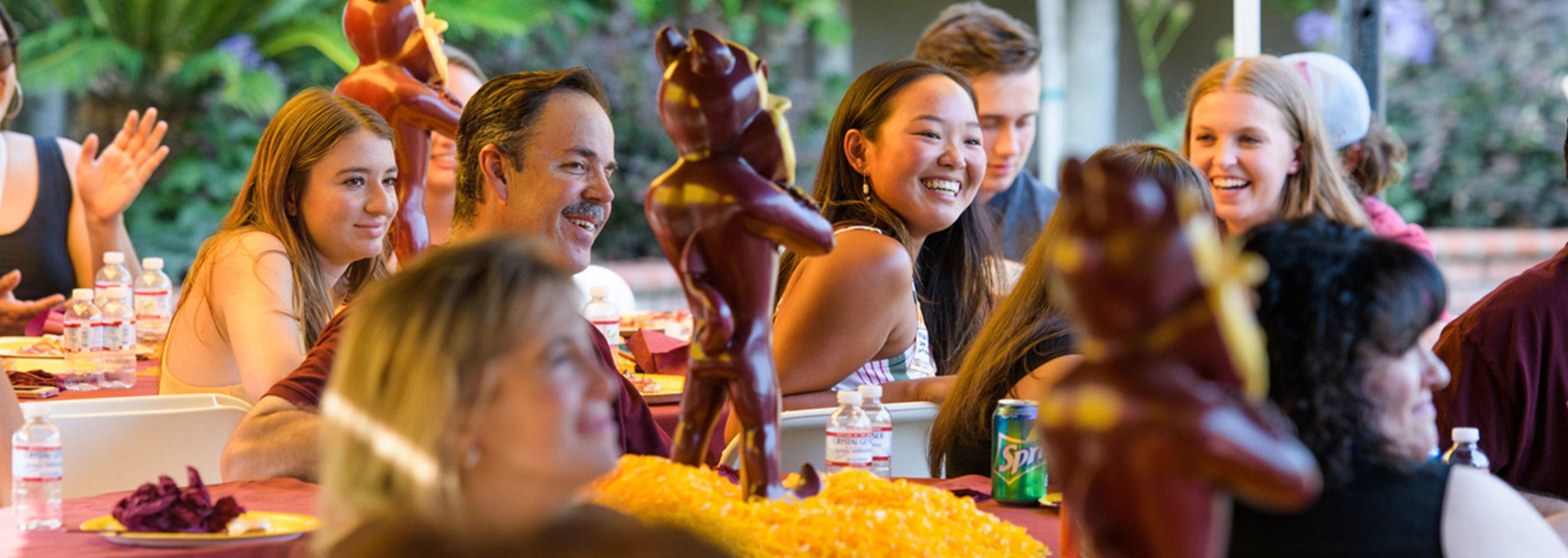 
		ASU alumni laugh and smile at event tables.		