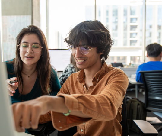 Two students in the Howard Center collaborate at a computer.