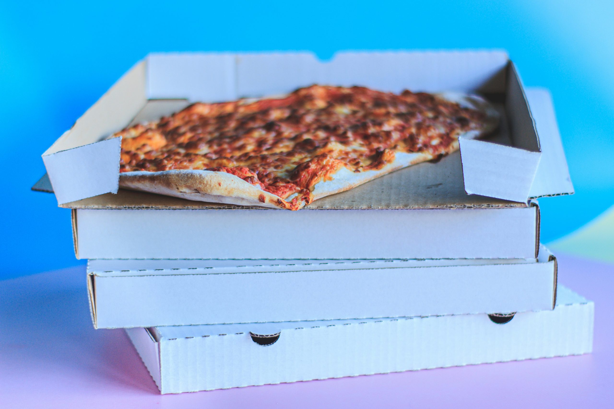 A stack of pizza boxes with a pizza on top.