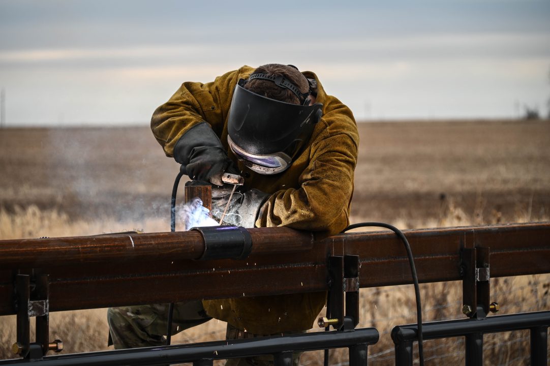 A welder in protective great welds outside.