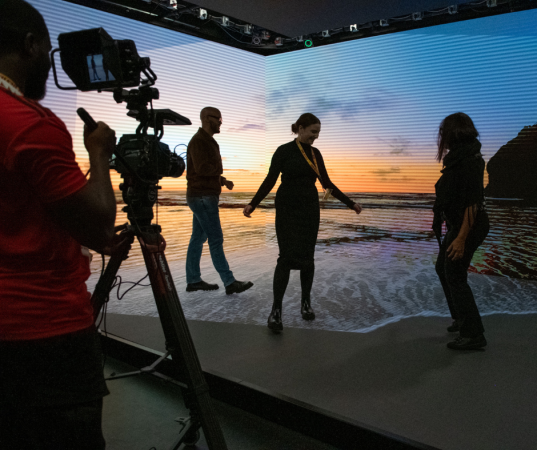 Three students try out a 3D stage with virtual beach content