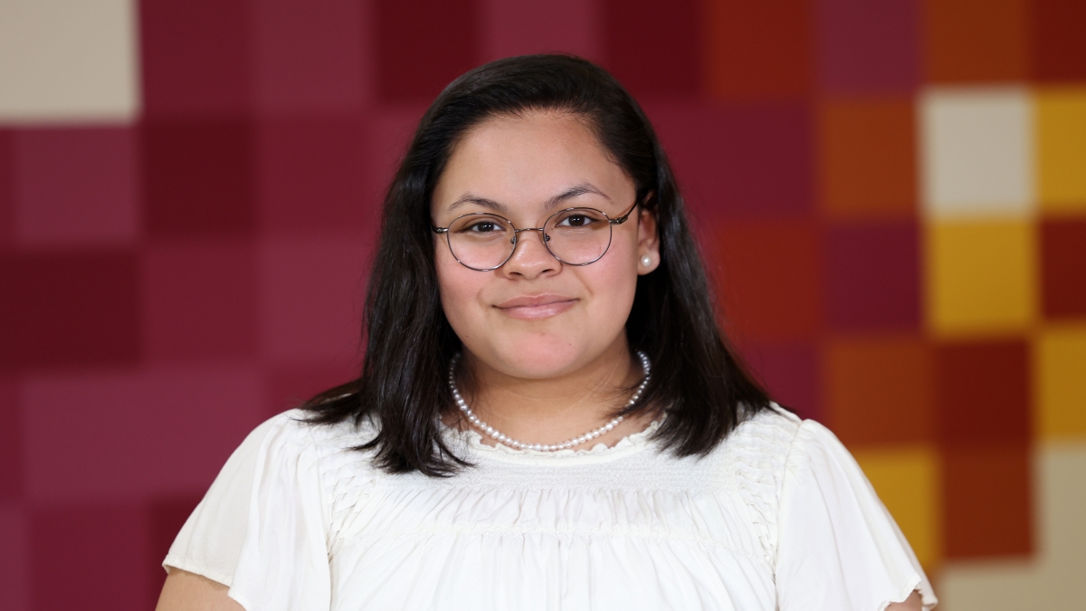 Alicia Rodriguez wears a white shirt and poses in front of a maroon background.