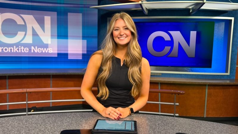 Kendall Flynn poses at the anchor desk in the Cronkite News studio