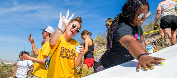 A student gives a "forks up" with a white-paint-covered hand.