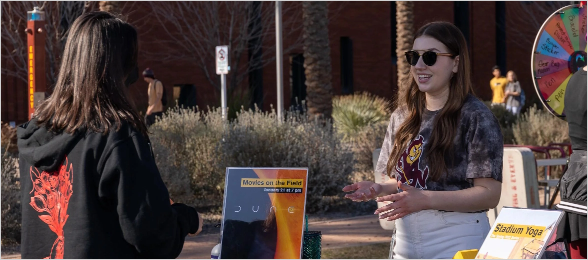 Two students chat at a tabling event.
